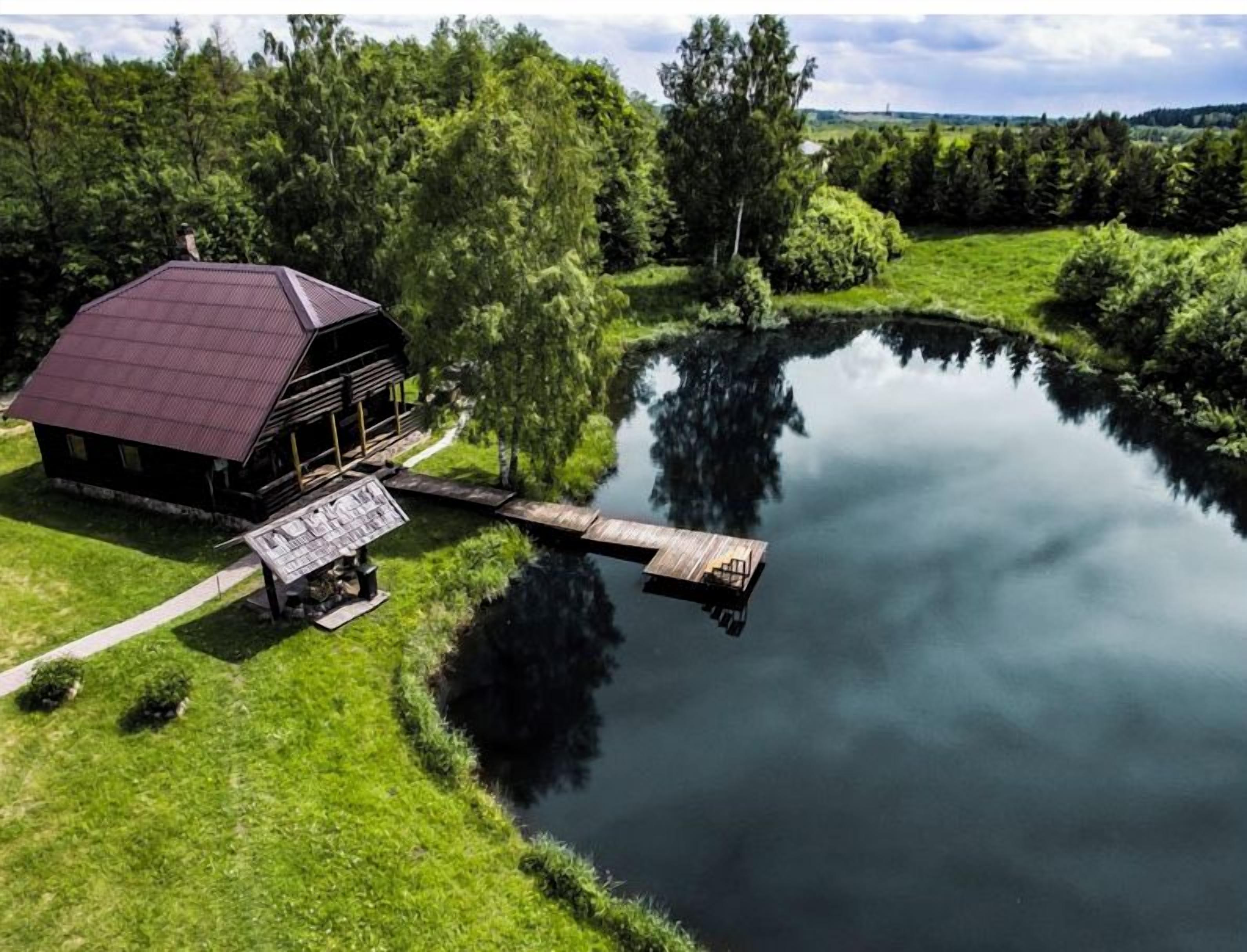 Eine Blockhütte am Seeufer mit einem Steg, der ins Wasser ragt, umgeben von üppiger Vegetation.