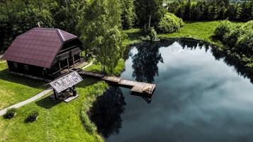 Eine Blockhütte am Seeufer mit einem Steg, der ins Wasser ragt, umgeben von üppiger Vegetation.