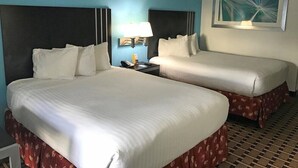 A hotel room with two beds, a nightstand, a lamp, and a painting on the wall.