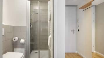 A modern bathroom with a toilet, shower, and a glass-enclosed shower stall.