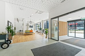Eine moderne Lobby mit Holzboden, einer Sitzecke und einer Glastür zum Außenbereich.
