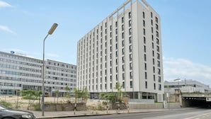 Un immeuble moderne de grande hauteur, doté d’une façade à fenêtres disposées en réseau et d’un toit plat.