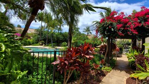 A lush garden with a pool, palm trees, and vibrant flowers.