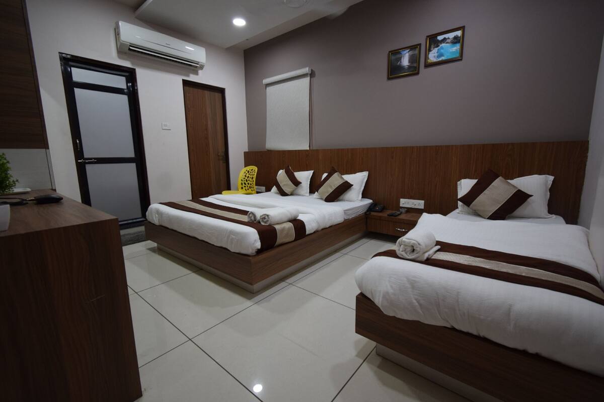 A hotel room with two beds, a desk, and a chair.