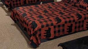A room with three beds, each covered with a red and black checkered blanket, and a black couch. - Beautiful house on the Paradise Eckerman boarder. (Eckerman)