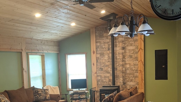A cozy living room with wooden floors, a stone fireplace, and a large clock on the wall. - Beautiful house on the Paradise Eckerman boarder. (Eckerman)