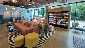 A modern lobby with a seating area, a beverage bar, and a large window offering a view of the outdoors. - Holiday Inn - the niu, Belt Frankfurt Eschborn by IHG (Eschborn)