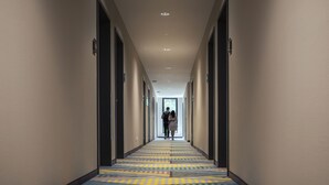 A hotel corridor with a patterned carpet, doors on both sides, and a view into a room at the end. - Holiday Inn - the niu, Belt Frankfurt Eschborn by IHG (Eschborn)