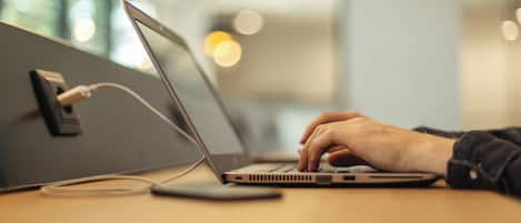 Una computadora portátil sobre una mesa, con una mano escribiendo.