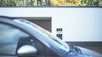 Une voiture est garée devant un immeuble sur lequel on peut lire l’inscription « the nu ».