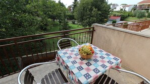 Un balcón con una mesa lista para una comida, con un frutero.