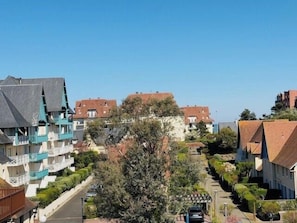 Una calle residencial con casas, cielo despejado y un camino bordeado de árboles.