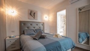 A bedroom with a large bed, a nightstand, a wall-mounted light, and a mirror. - Casa Anemona with terrace, shared pool, sea views and free wifi (Puerto del Carmen)