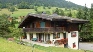 A traditional chalet with a balcony, wooden exterior, and flower boxes.
