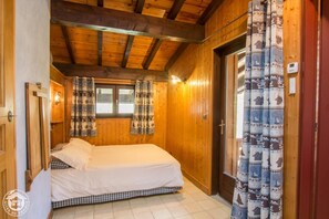 Una habitación de madera con cama, cortinas y un termostato en la pared.