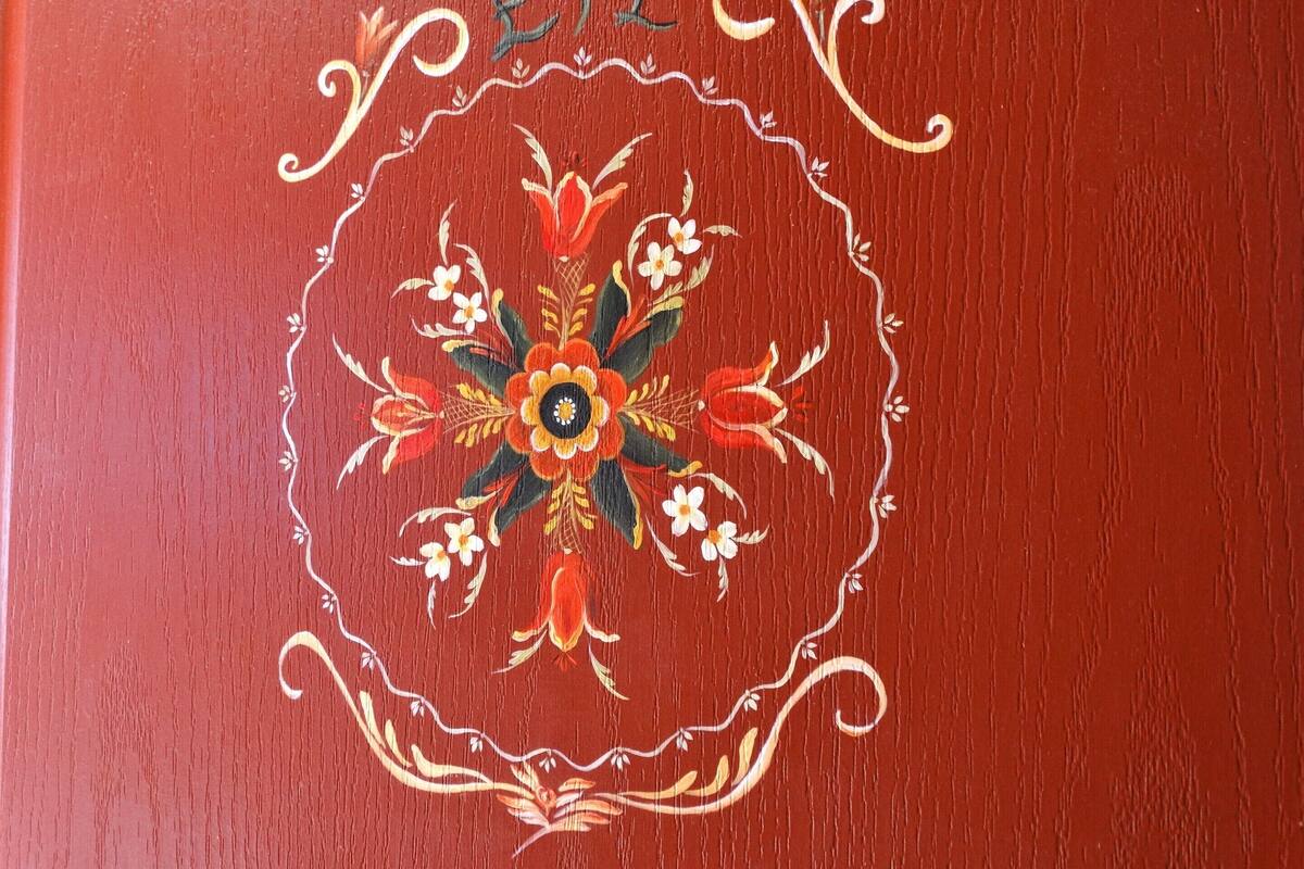 Ein roter Buchumschlag mit aufwendigen floralen Mustern und chinesischen Schriftzeichen.
