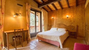 A wooden room with a bed, a desk, and two wall-mounted lights.