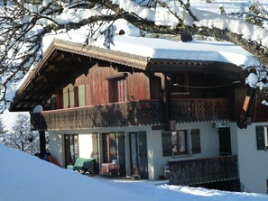 Un chalet de madera con balcón, paisajes nevados y vista despejada al interior.