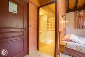 Una puerta de madera con una placa, un baño con revestimiento de pared a cuadros y una cama con almohadas.