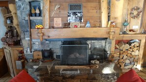 A cozy living room with a stone fireplace, wooden shelves, and a red couch.