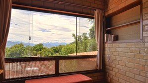 A room with a large window overlooking a mountainous landscape, a wooden ceiling, and a brick wall with a shelf. - Naturaleza, Playas, Trecking, Mata Atlantica, Familia y Mascotas Pequeñas Bienve (vila abraoo)