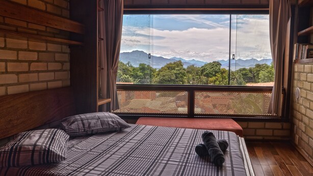 A room with a bed, a view of mountains, and a balcony with a lattice railing. - Naturaleza, Playas, Trecking, Mata Atlantica, Familia y Mascotas Pequeñas Bienve (vila abraoo)
