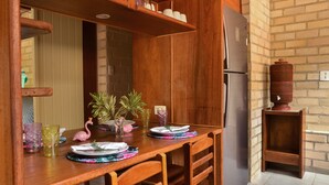 A wooden dining table with plates, glasses, and a flamingo figurine. - Naturaleza, Playas, Trecking, Mata Atlantica, Familia y Mascotas Pequeñas Bienve (vila abraoo)
