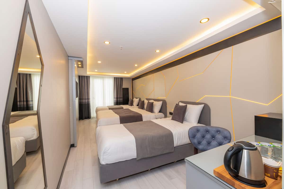 A modern hotel room with two beds, a seating area, a coffee machine, and a large mirror.