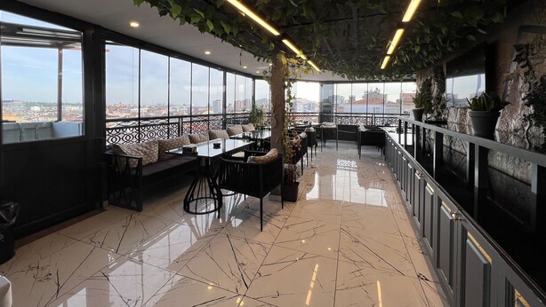 En modern takterrass med en fantastisk panoramautsikt över staden, som erbjuder en blandning av olika sittgrupper och ett område för att äta.
