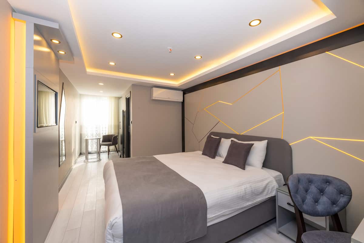 A modern bedroom with a large bed, bedside tables, a chair, and a geometric wall design.