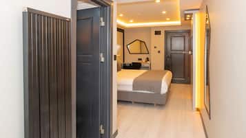Quarto de hotel moderno com cama, mesa de cabeceira e um espelho grande na parede.