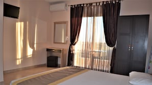 Una habitación de hotel con una cama, un escritorio, una silla, un armario y un televisor.