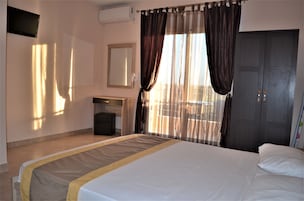 Una habitación de hotel con una cama, un escritorio, una silla, un armario y un televisor.
