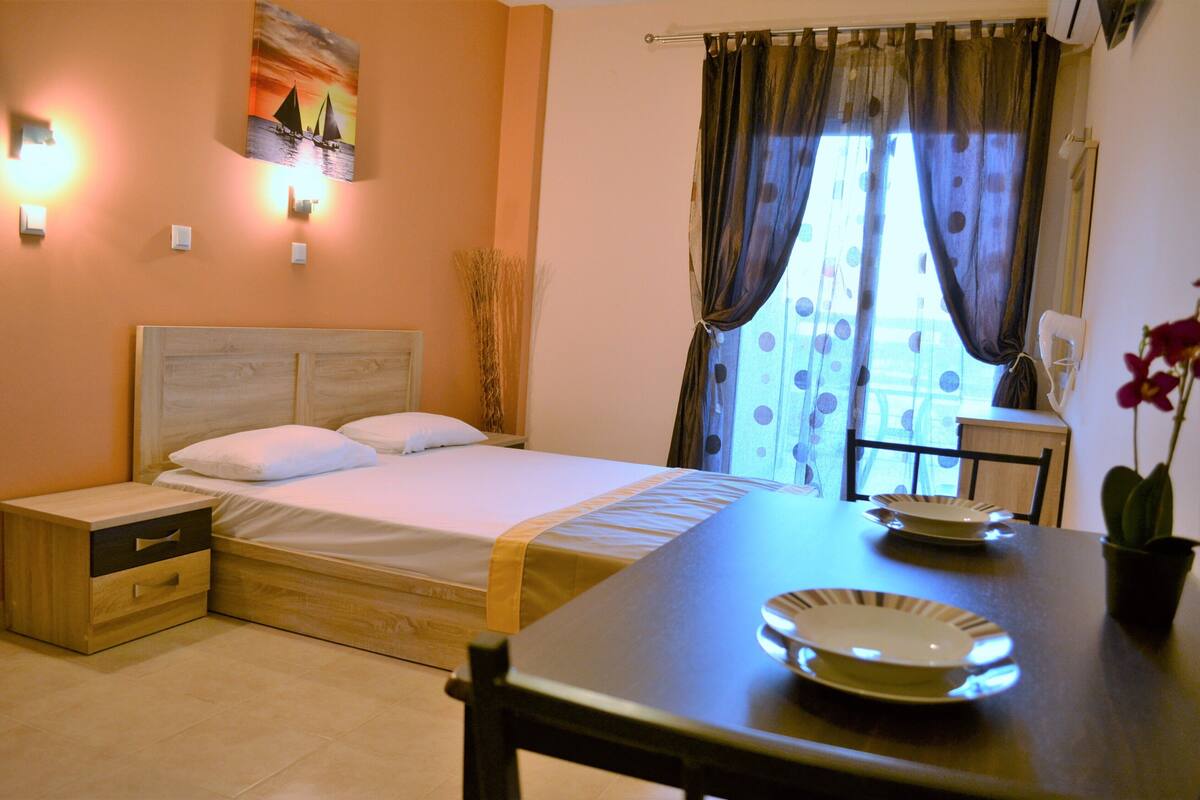 A bedroom with a bed, bedside table, and a dining table with plates.