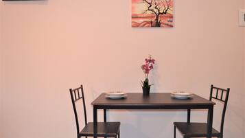 Una mesa de comedor con dos sillas, una planta en maceta y un cuadro en la pared.