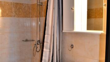 A bathroom with a shower, a sink, and a mirror with lights.
