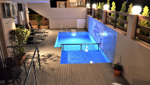 Un área de piscina en la azotea con un trampolín, sillas de descanso y plantas en macetas.