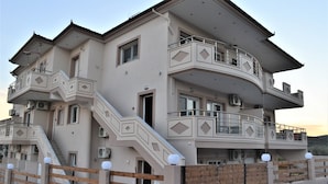 Un edificio residencial de varios pisos con balcones, escaleras y una entrada protegida por un portón.