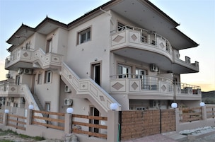 Un edificio residencial de varios pisos con balcones, escaleras y una entrada protegida por un portón.