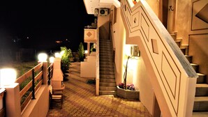 Vista nocturna del exterior de un edificio con una escalera que conduce a un segundo piso.