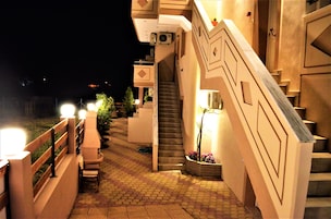 Vista nocturna del exterior de un edificio con una escalera que conduce a un segundo piso.