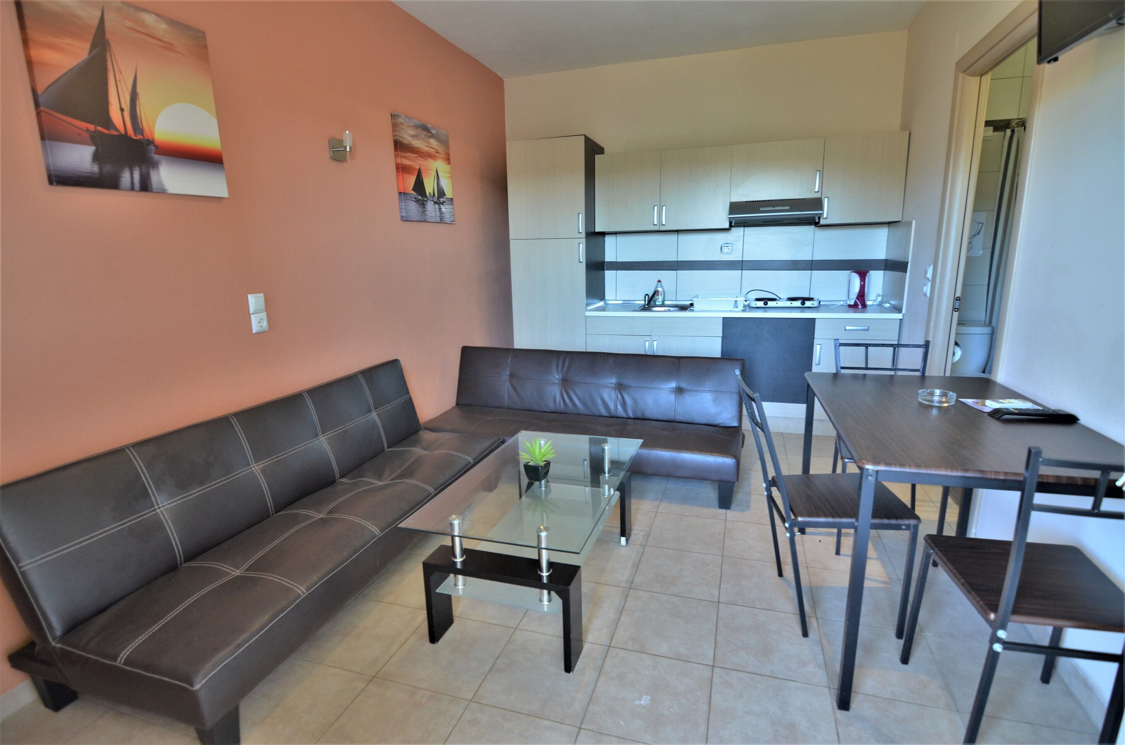 A living room with a sofa, a glass coffee table, and a dining table with chairs.