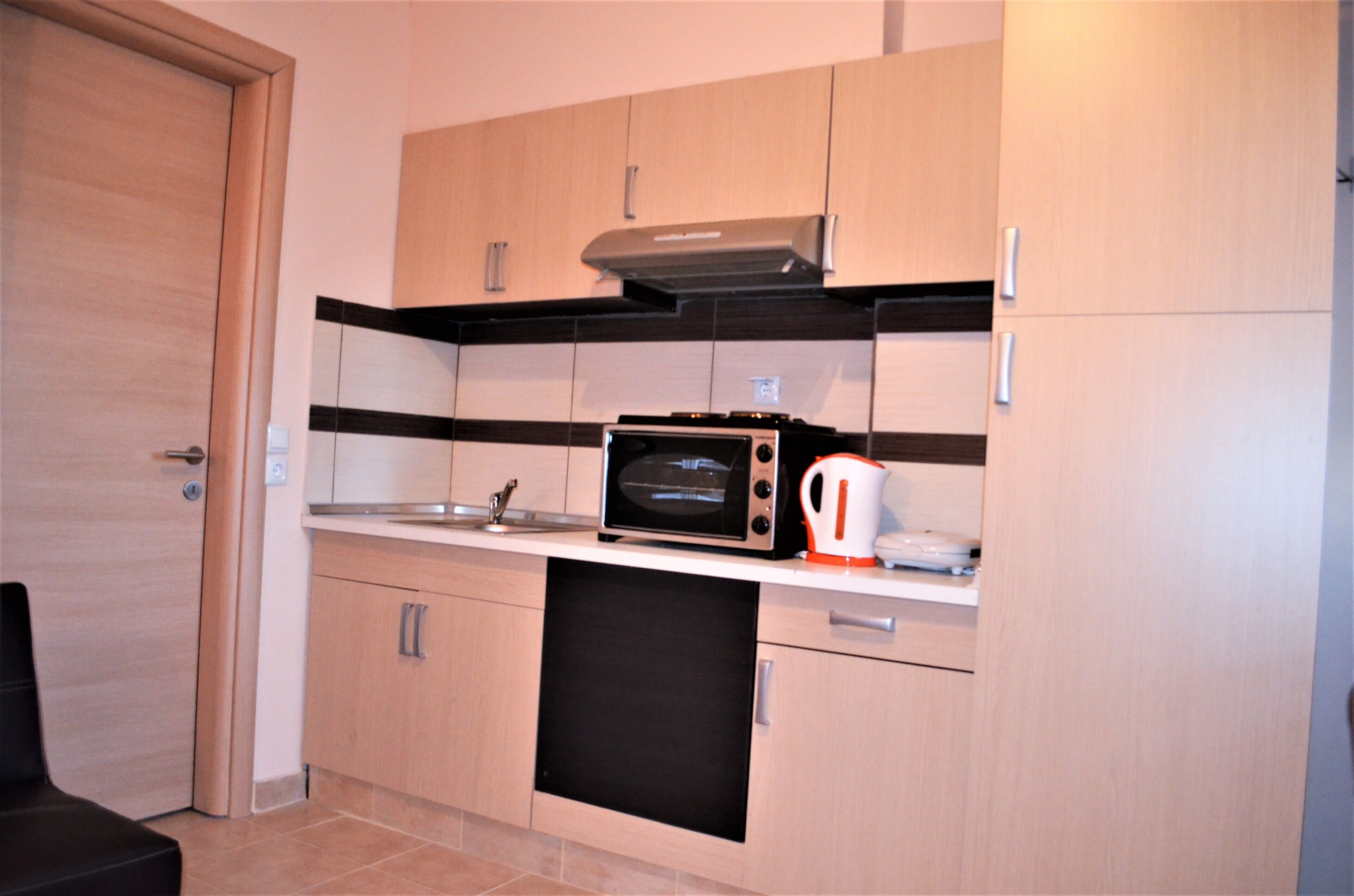 A compact kitchen with a microwave, kettle, and a dishwasher.