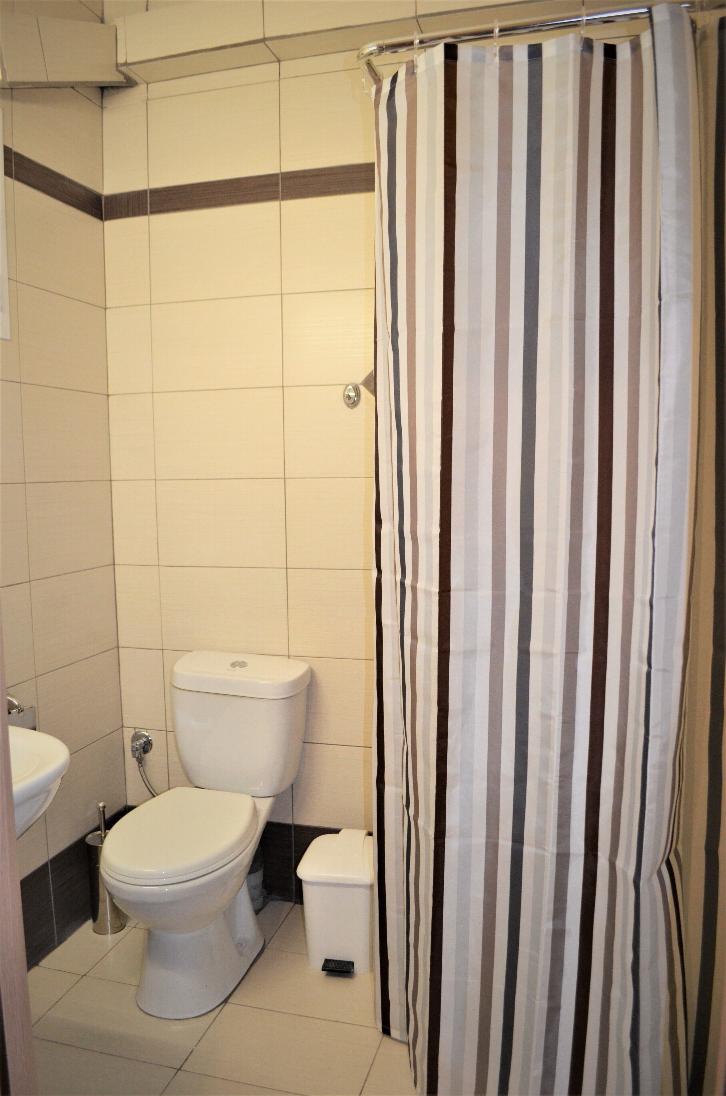 A bathroom with a toilet, sink, and striped shower curtain.