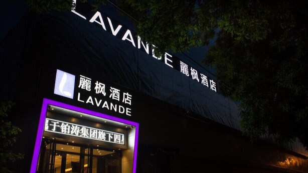 Un hôtel appelé LAVANDE, avec une enseigne bien visible et une entrée illuminée par des néons.