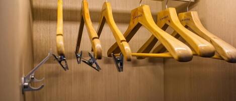 A wooden coat rack with multiple hangers, some with metal clips.