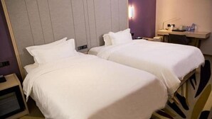 Une chambre d’hôtel avec deux lits, une table de chevet, un bureau et une lampe fixée au mur.