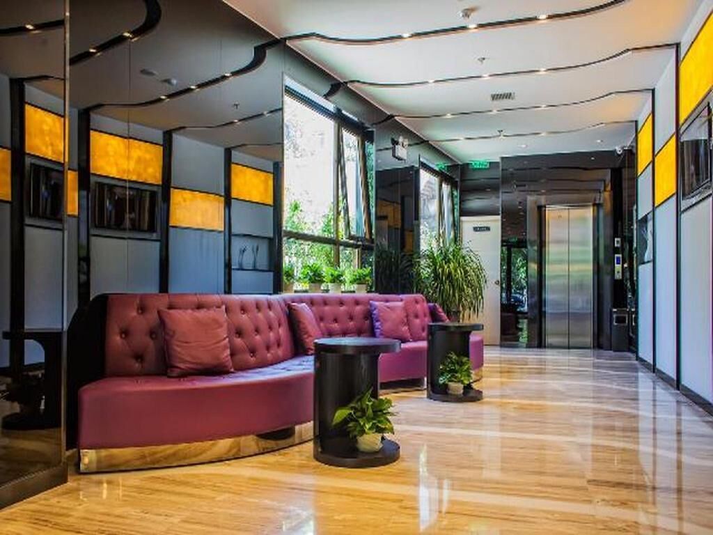 A modern lobby with a red sofa, black side tables, and potted plants.