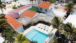 Ein Resort mit Swimmingpool, strohgedeckten Gebäuden und Palmen.