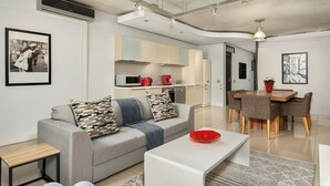 Ein modernes Wohnzimmer mit einem grauen Sofa, einem weißen Couchtisch und einem Essbereich mit Holztisch und Stühlen.